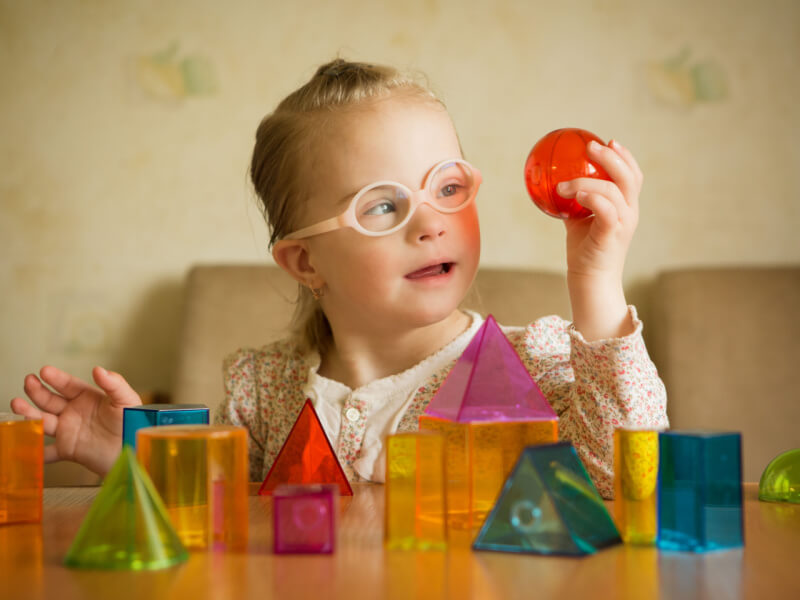 Menina com síndrome de Down jogando com formas geométricas