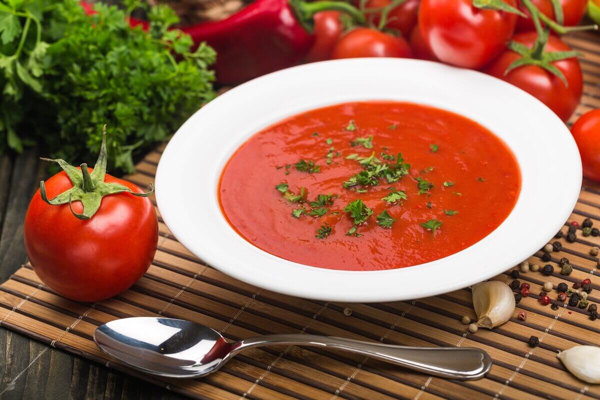 Sopa de tomate polvilhada com coentro picado em um prato branco