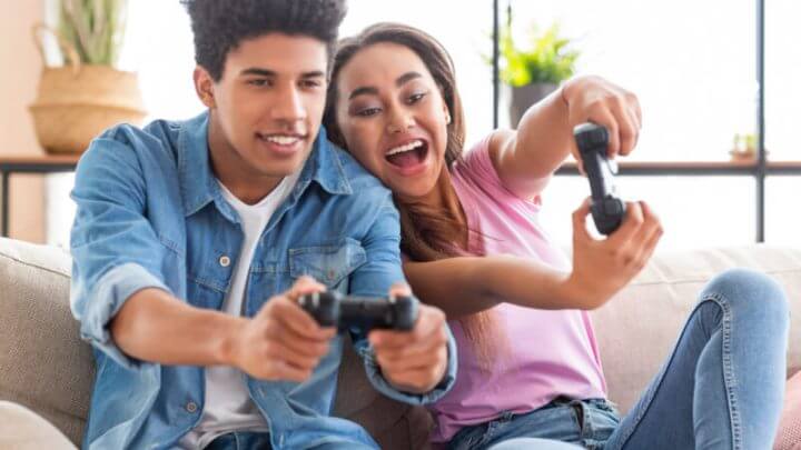 Menino e menina jogando videogame sentados no sofá