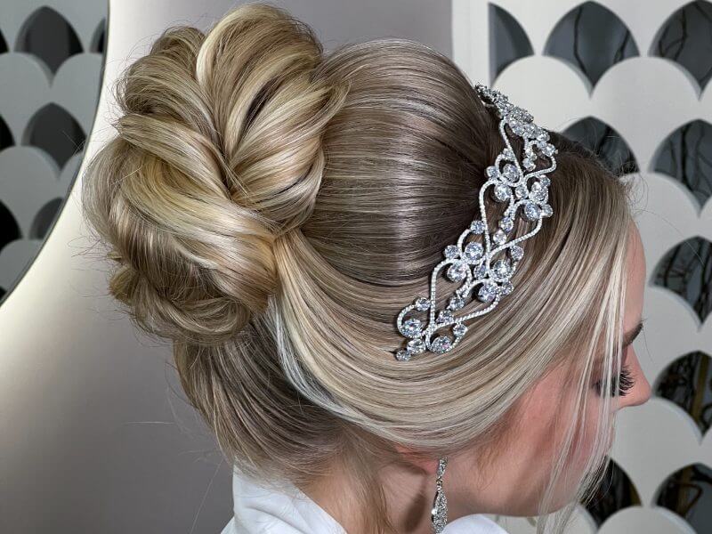 Noiva de lado com coque no cabelo e tiara de brilhantes