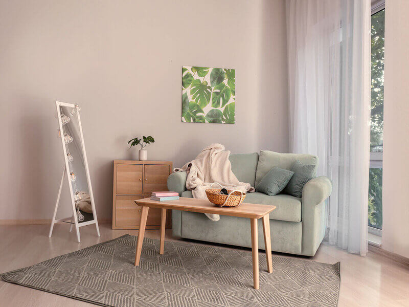 Sala de estar com parede rosa, sofá cinza e mesa de centro de madeira