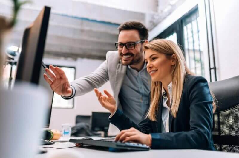 Homem e mulher em ambiente de trabalho analisando dados no computador
