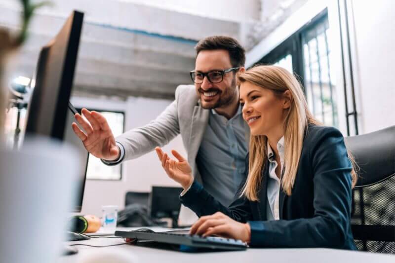 Homem e mulher em ambiente de trabalho analisando dados no computador