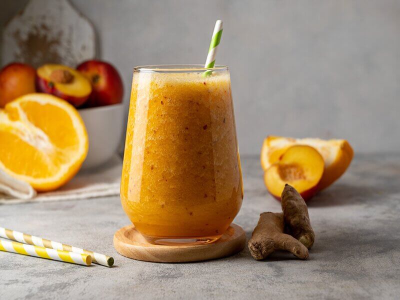 Copo de vidro com suco de pêssego, laranja e gengibre