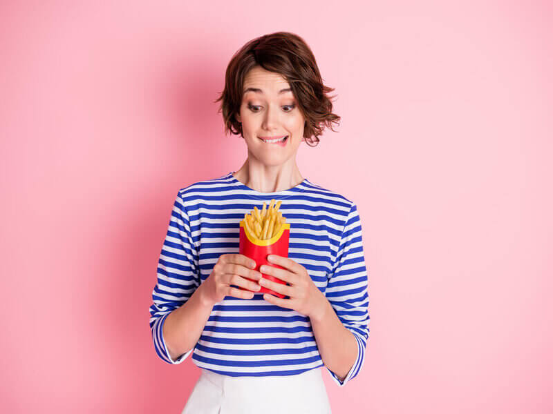 Mulher segurando e olhando para batatas-fritas