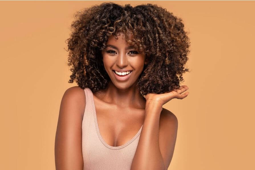 Mulher com cabelo cacheado e iluminado na altura do ombro