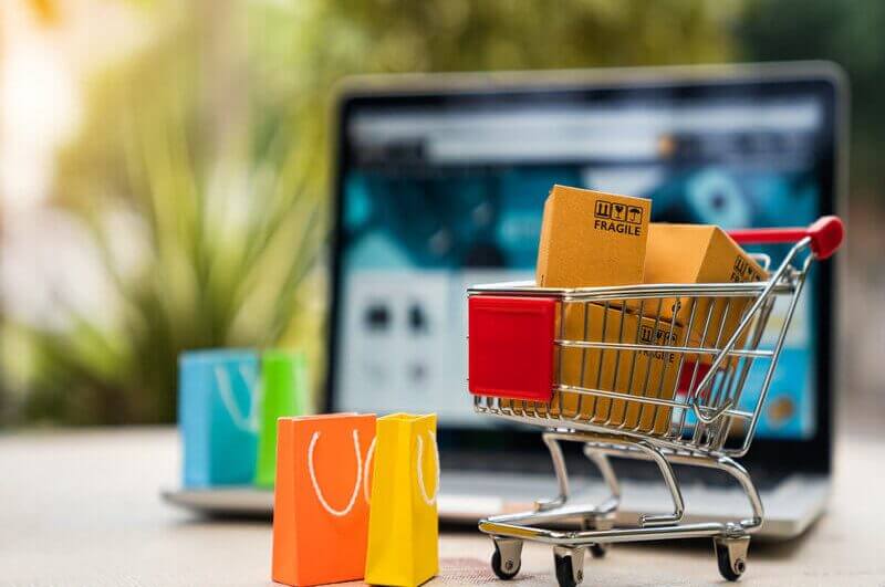 Carrinho pequeno com caixas de compra e sacolas em cima de uma mesa com notebook