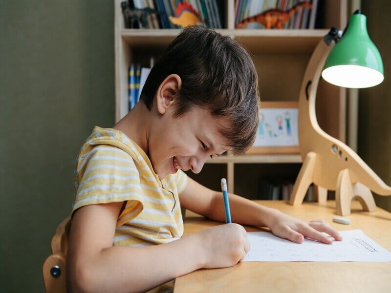 Menino sorrindo sentado estudando