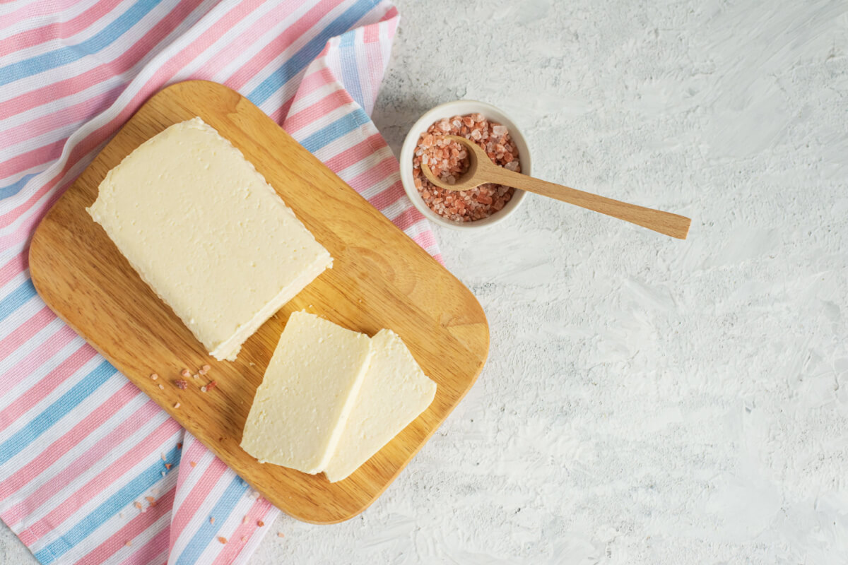 Queijo de tofu cortado em tábua de madeira ao lado de especiarias
