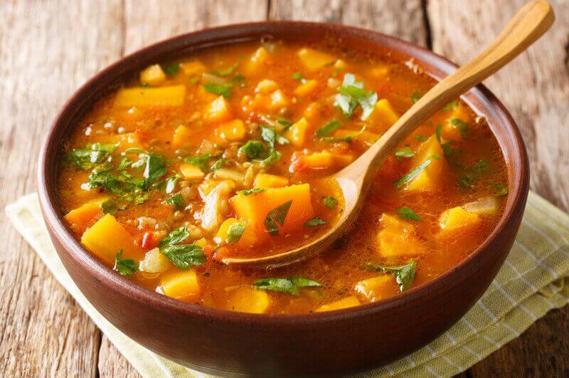 Recipiente marrom com sopa de batata-doce polvilhada com coentro