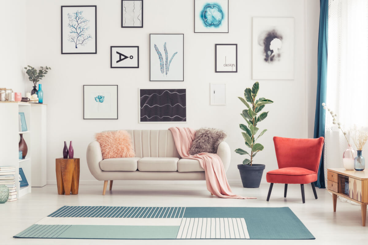 Cadeira vermelha e tapete azul perto de sofá no interior da sala de estar colorida com figuras estampadas na parede