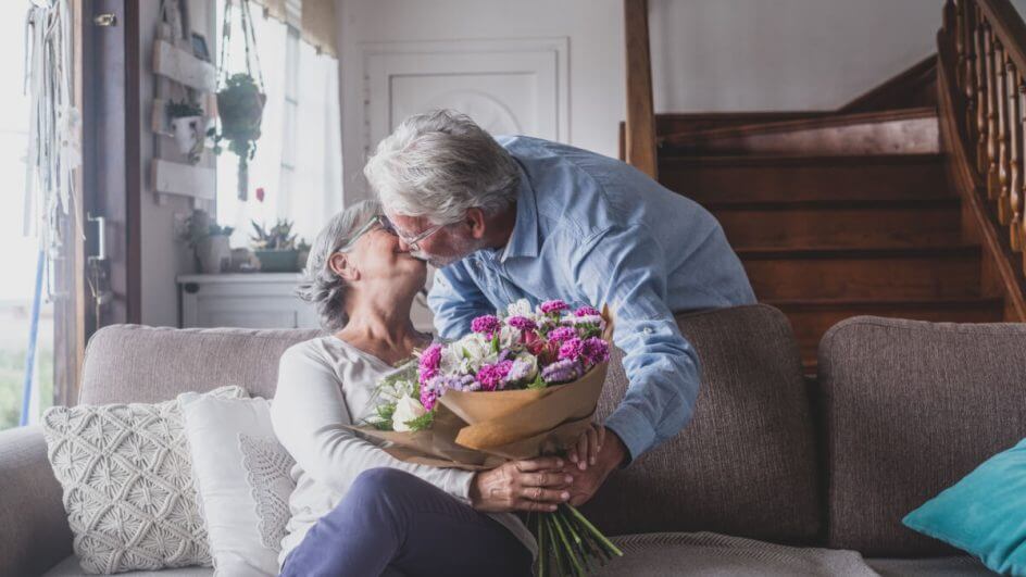 Homem idoso dando flores para sua esposa