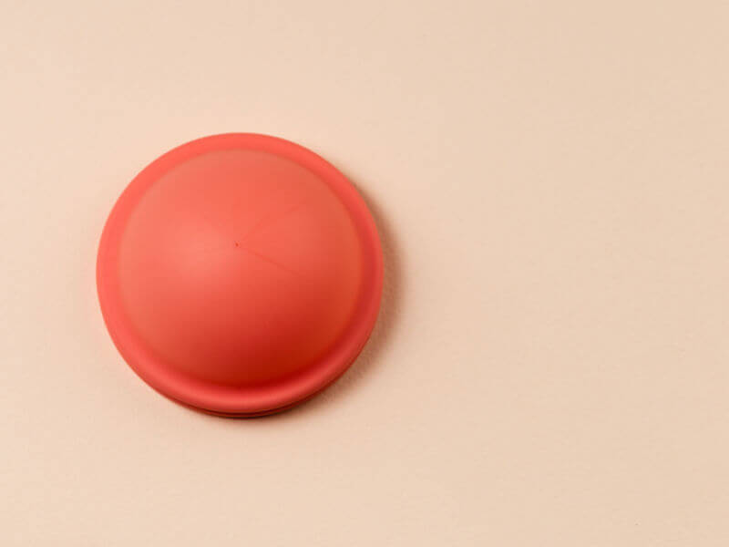 disco menstrual laranja em fundo rosa