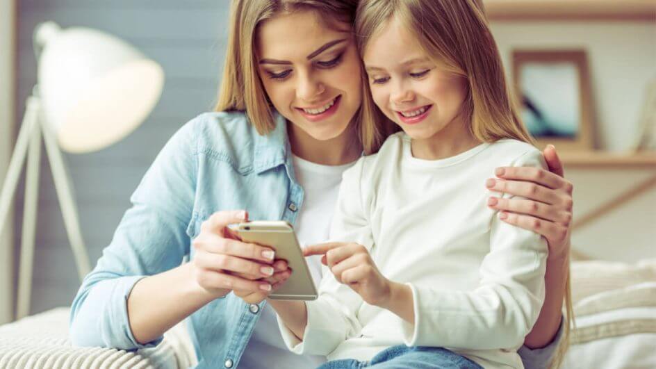 Mãe jovem e sua filhinha estão usando um smartphone