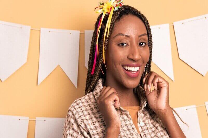 Mulher com blusa xadrez sorrindo e usando mini chápeu nos cabelos
