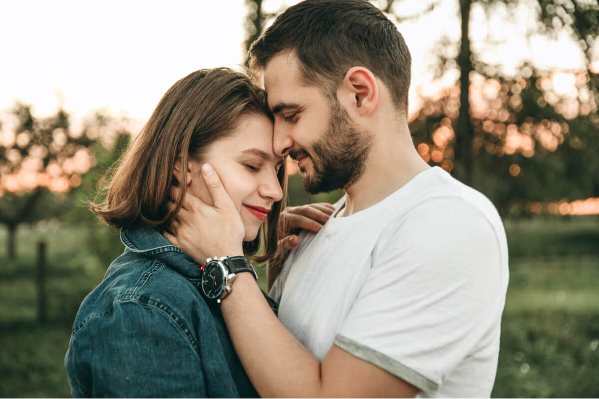 Casal em um parque com os rosto colados