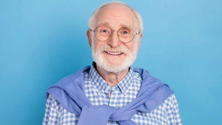 Homem idoso de óculos e blusa xadrez sorrindo