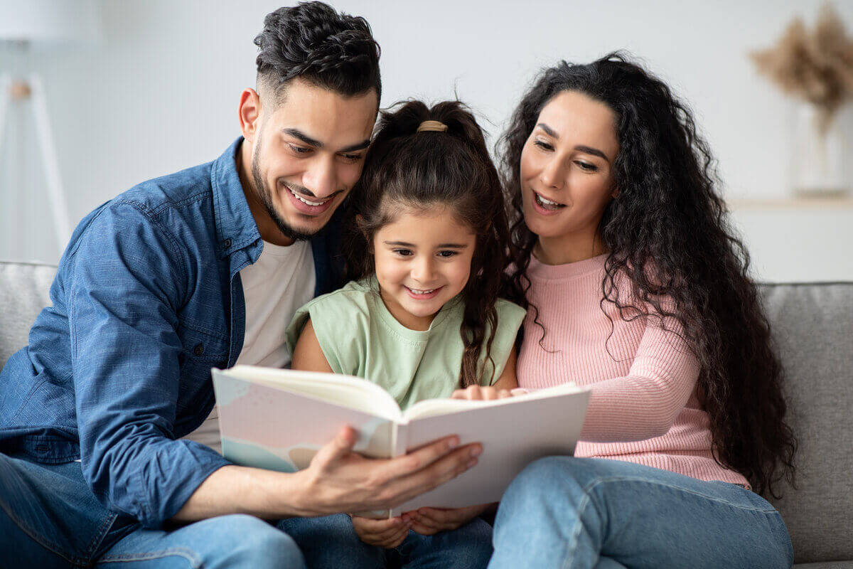 Homem e mulher lendo livro para uma menina