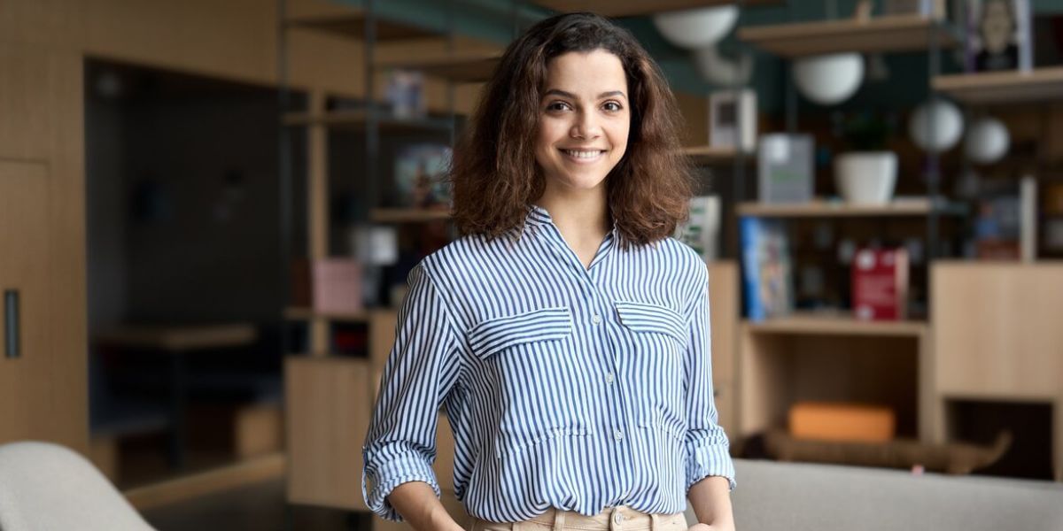 Mulher com roupa social de braços cruzados em pé