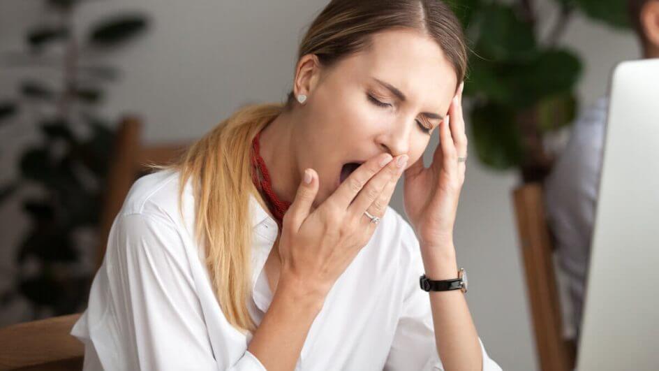 Mulher bocejando com a mão na boca e cabeça