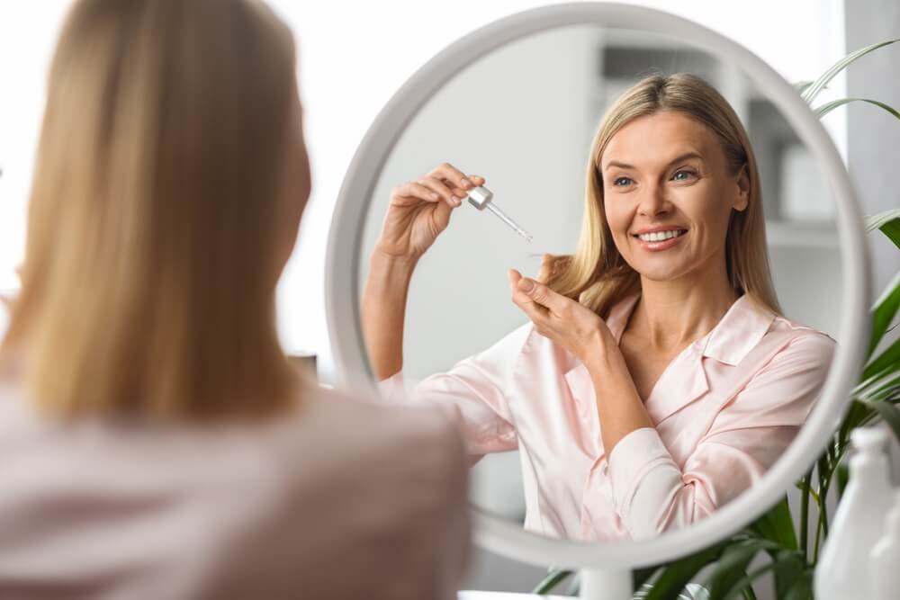 Mulher loira aplicando produto nos cabelos
