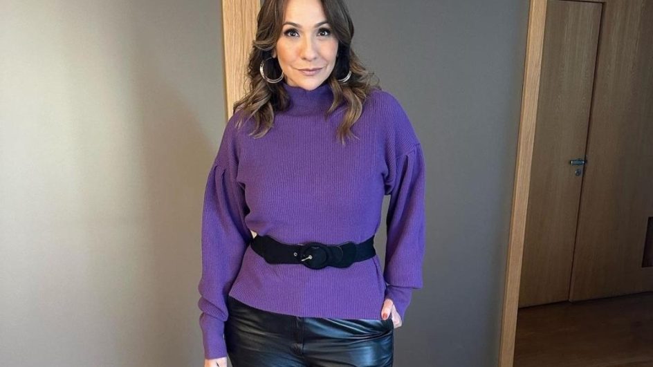 Maria Beltrão vestindo blusa rosa e calça preta posando para foto com a mão no bolso