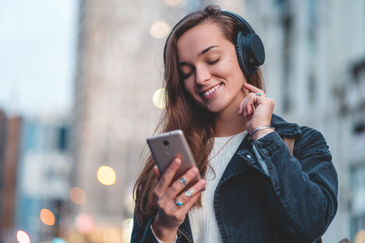 Menina mexendo no celular e usando fone de ouvido na rua