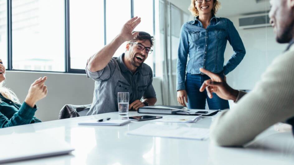 Colaboradores sorridentes em uma sala de reunião