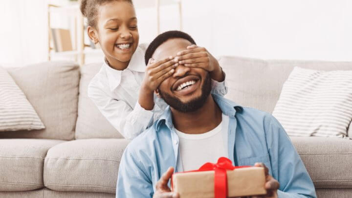 Filha feliz parabenizando pai e dando presente em casa