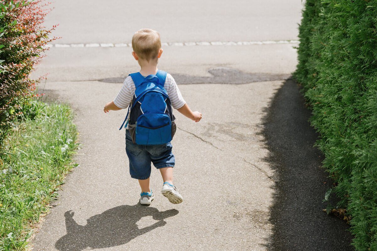 Garoto pequeno de costas andando com mochila azul