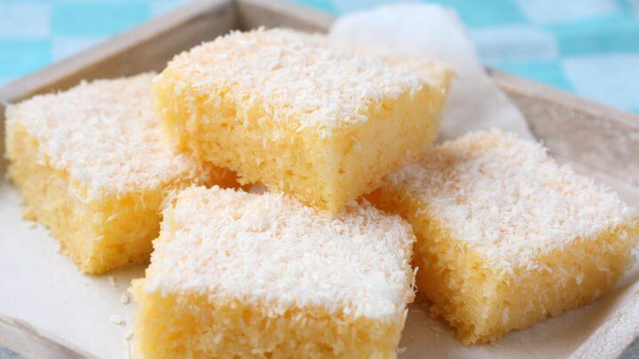 Pedaços de bolo de coco polvilhados com coco em cima de um prato branco