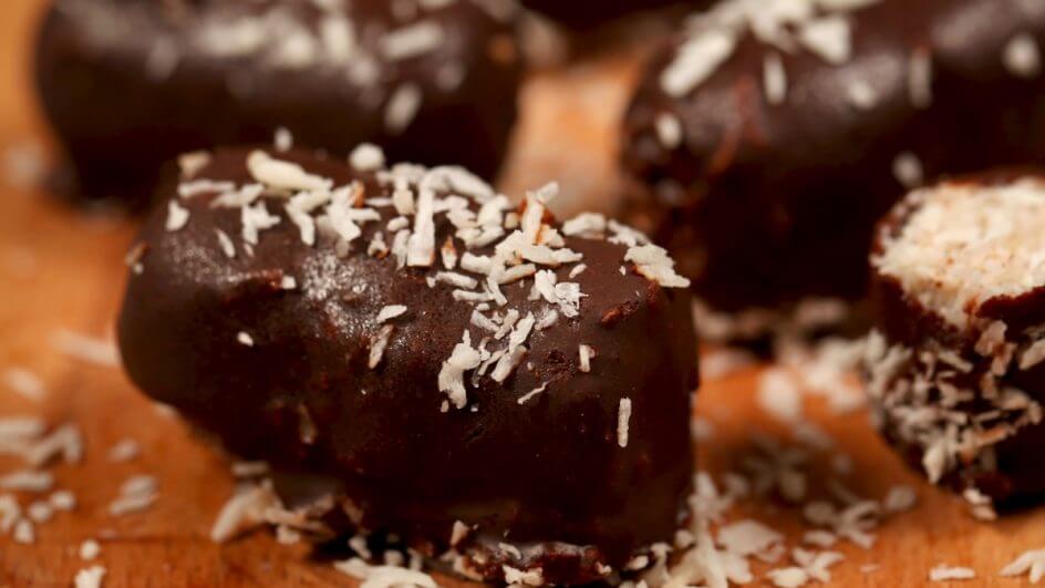Bombons de chocolate com coco em cima de uma mesa de madeira com coco ralado