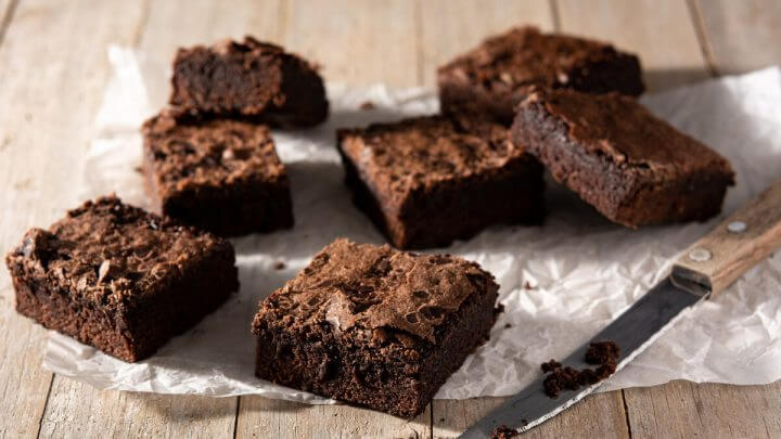 Brownies em cima de um papel de manteiga com uma faca ao lado