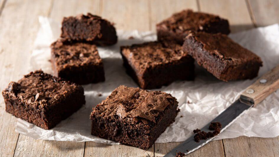 Brownies em cima de um papel de manteiga com uma faca ao lado