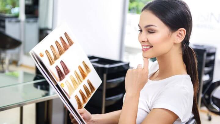 Cliente em salão de beleza segurando amostras de coloração de cabelo