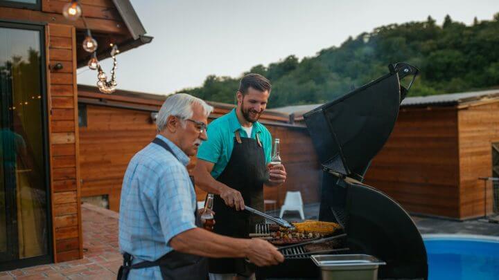 Dois homens fazendo churrasco em uma churrasqueira