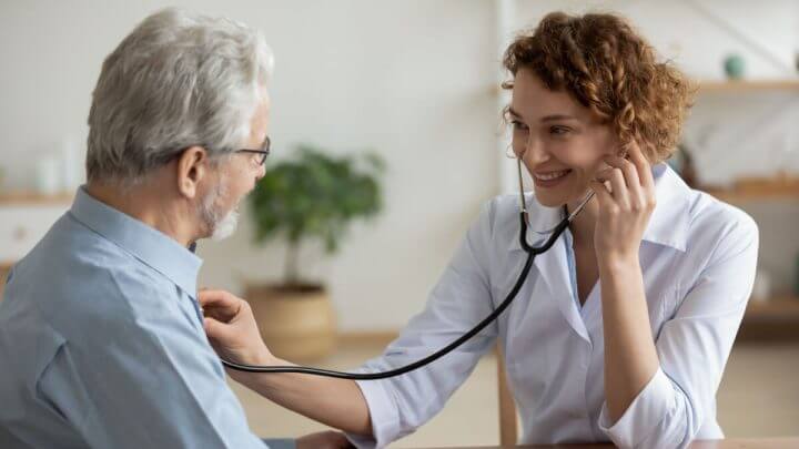 Médica examinando coração de homem em consultório