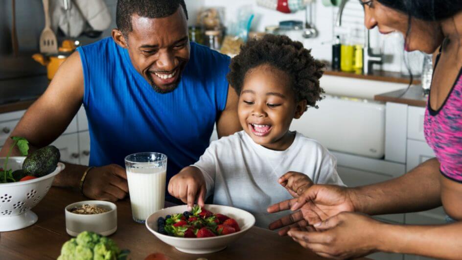Pais incentivando criança a comer alimentos saudáveis