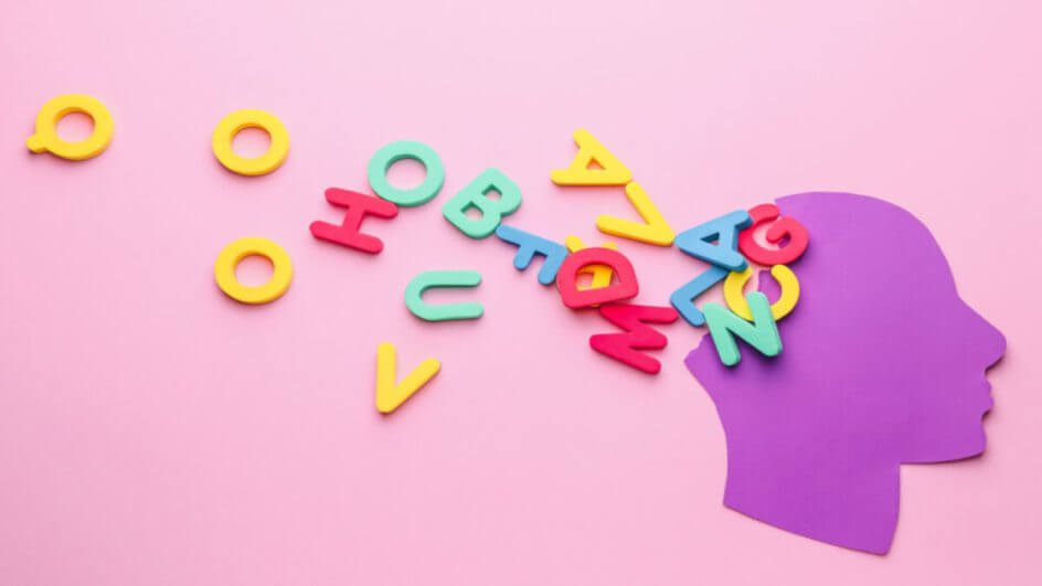 Ilustração de cabeça humana de papel com letras na cor de fundo, que é rosa