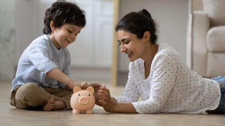 Mãe e filho colocando moedas em cofre de porquinho