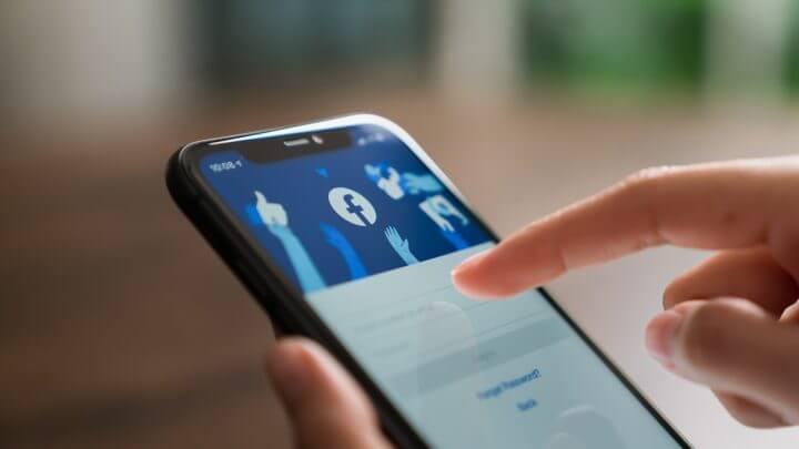 Pessoa segura celular com a tela de login do Facebook