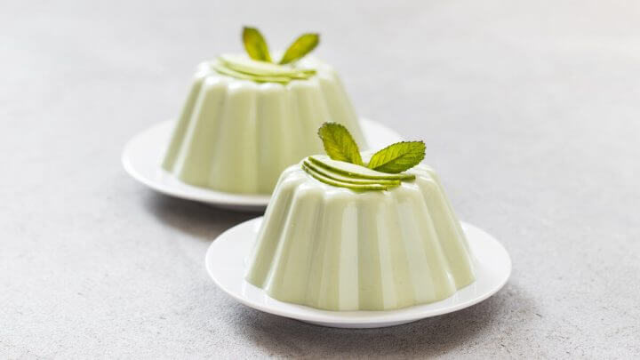 Dois flans de abacates decorados com folhas de hortelã e abacate em cima de uma mesa