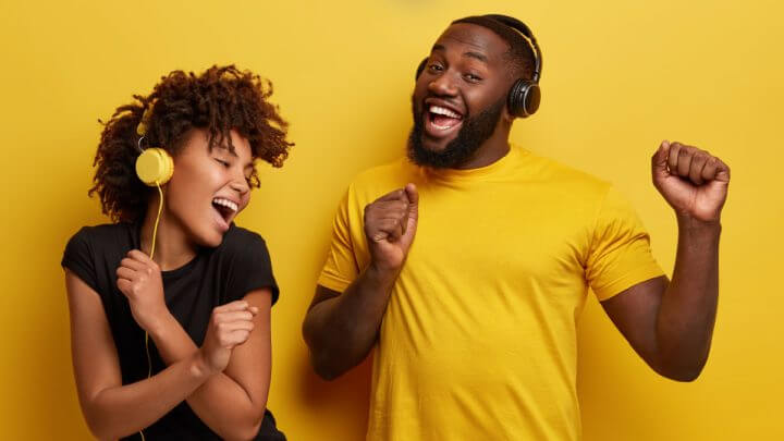 Mulher e homem em fundo amarelo com fones de ouvido