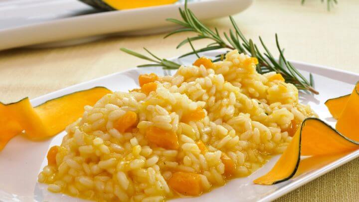 Prato branco com risoto de abóbora em cima de uma mesa