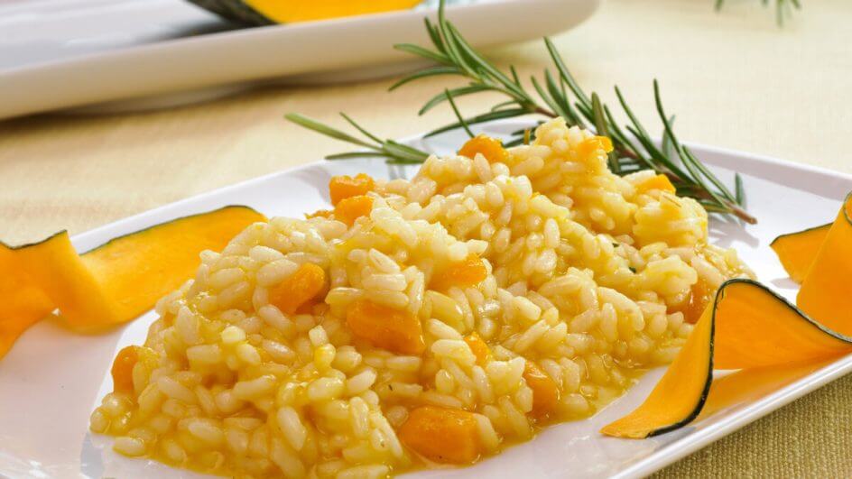 Prato branco com risoto de abóbora em cima de uma mesa