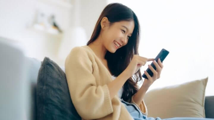 Mulher sentada sorrindo e mexendo no celular
