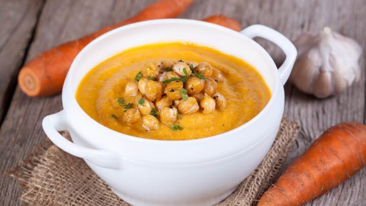Panela branca com sopa de grão-de-bico com cenoura