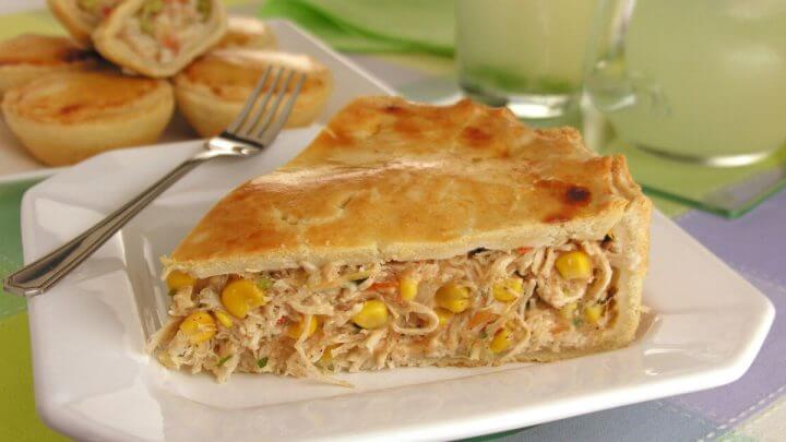 Pedaço de torta de frango com milho e cenoura em cima de um prato branco