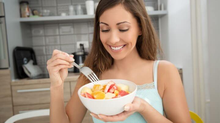 Mulher comendo salada de fruta