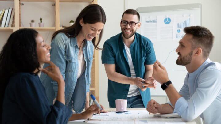 Colegas de trabalho sorrindo reunidos em sala de reunião